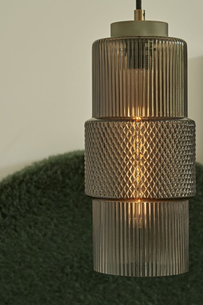 Up close image of a gold Smoked glass pendant with beautiful patterns adorned on it , emitting a warm glow.