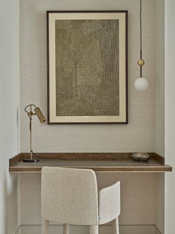 Study area in a neutral toned bedroom. An art piece is hung on the wall in front of the desk and also a J Adams sport light is placed on the desk.