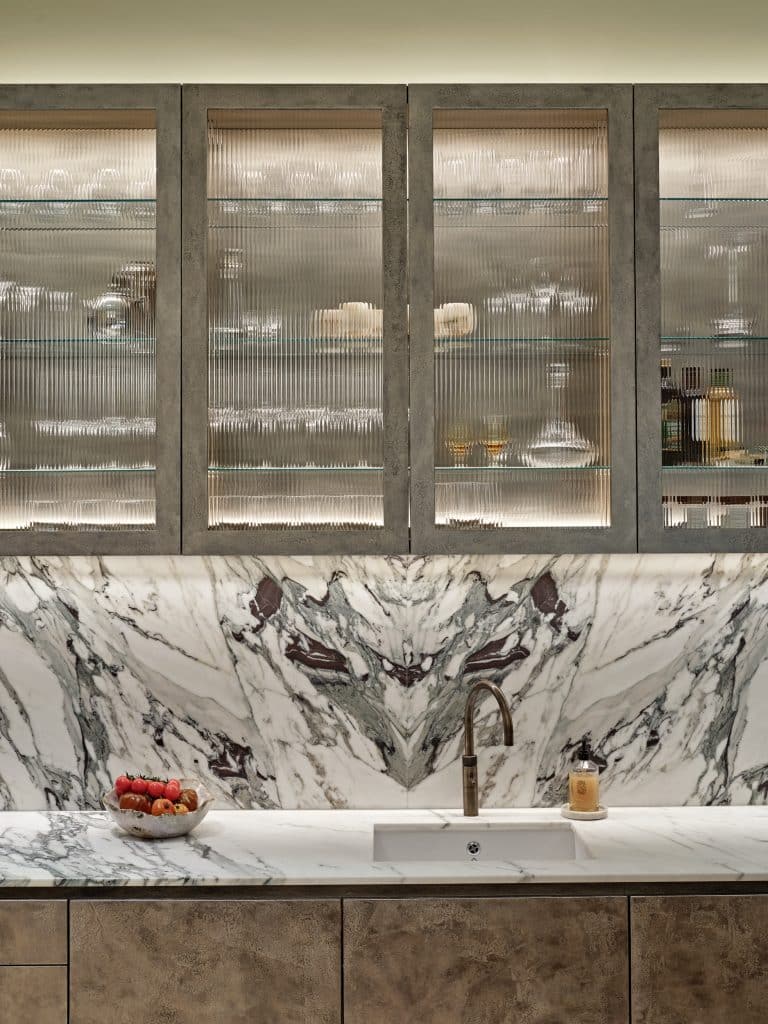 Marble kitchen counter and hand-painted pitted champagne liquid leaf finished cabinets.