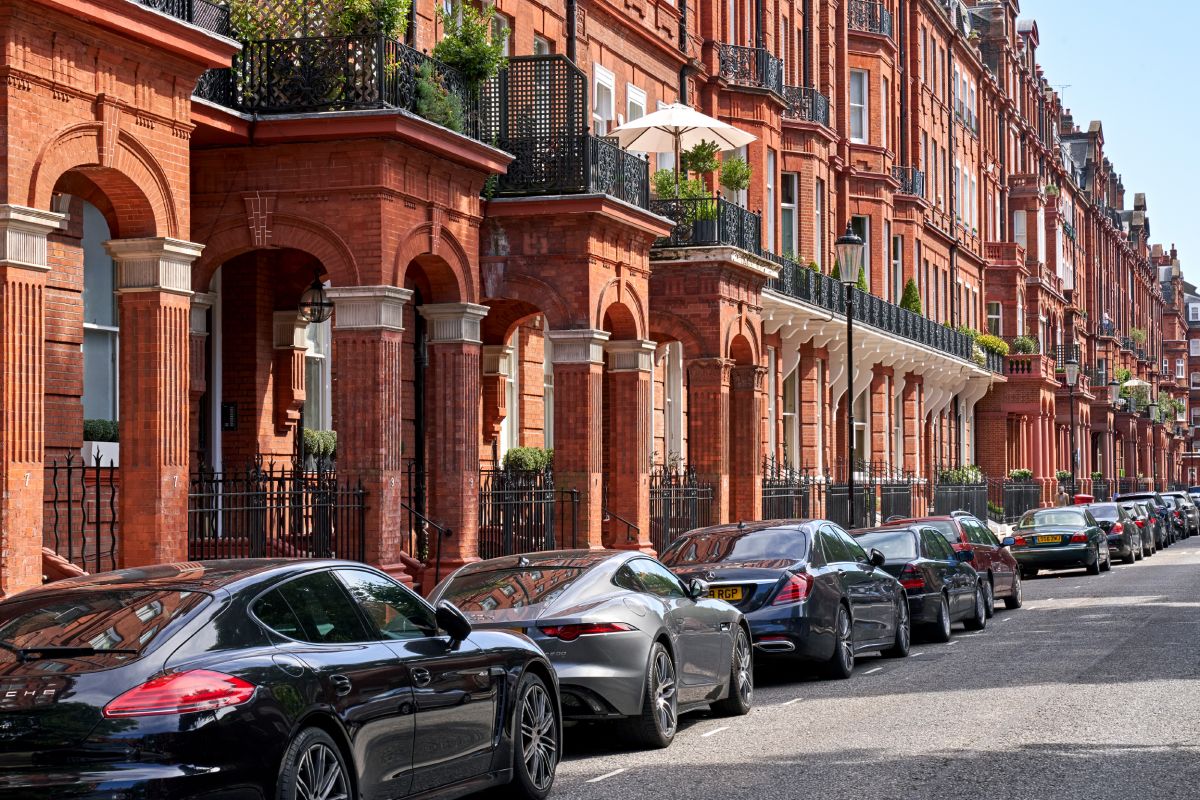 Cars parked on the side of traditional London properties.