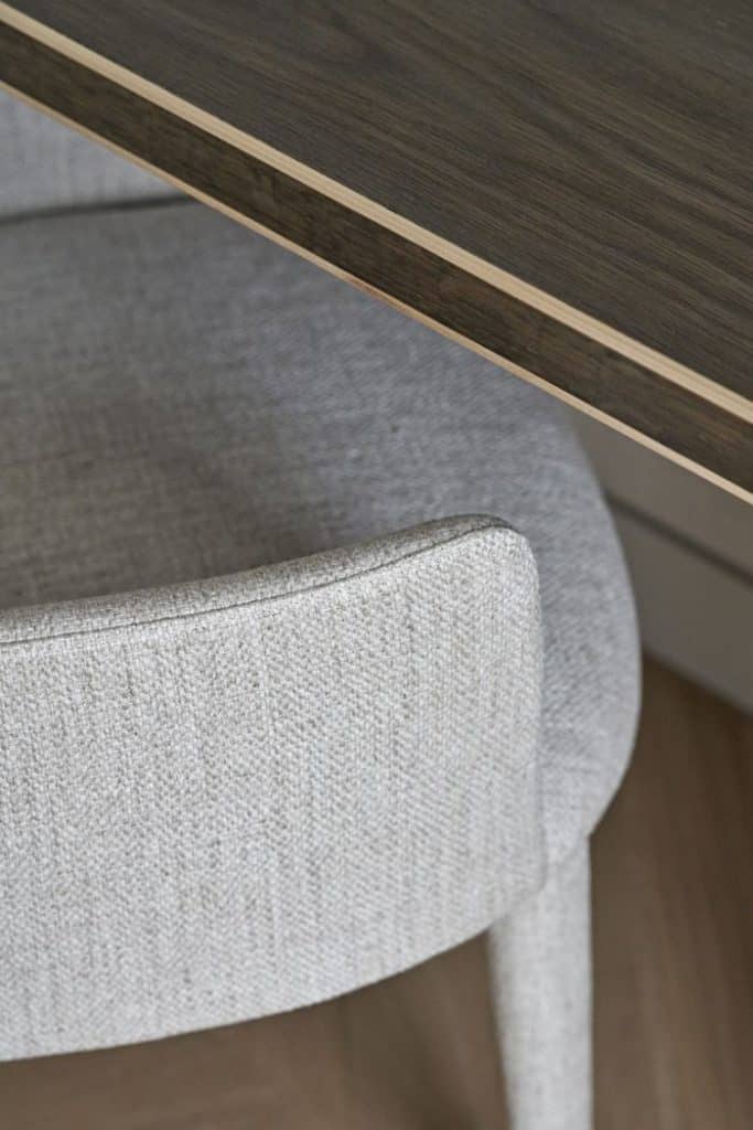 Close up image of a neutral grey toned desk chair from Lema, located in the home study, alongside a dark wood desk.