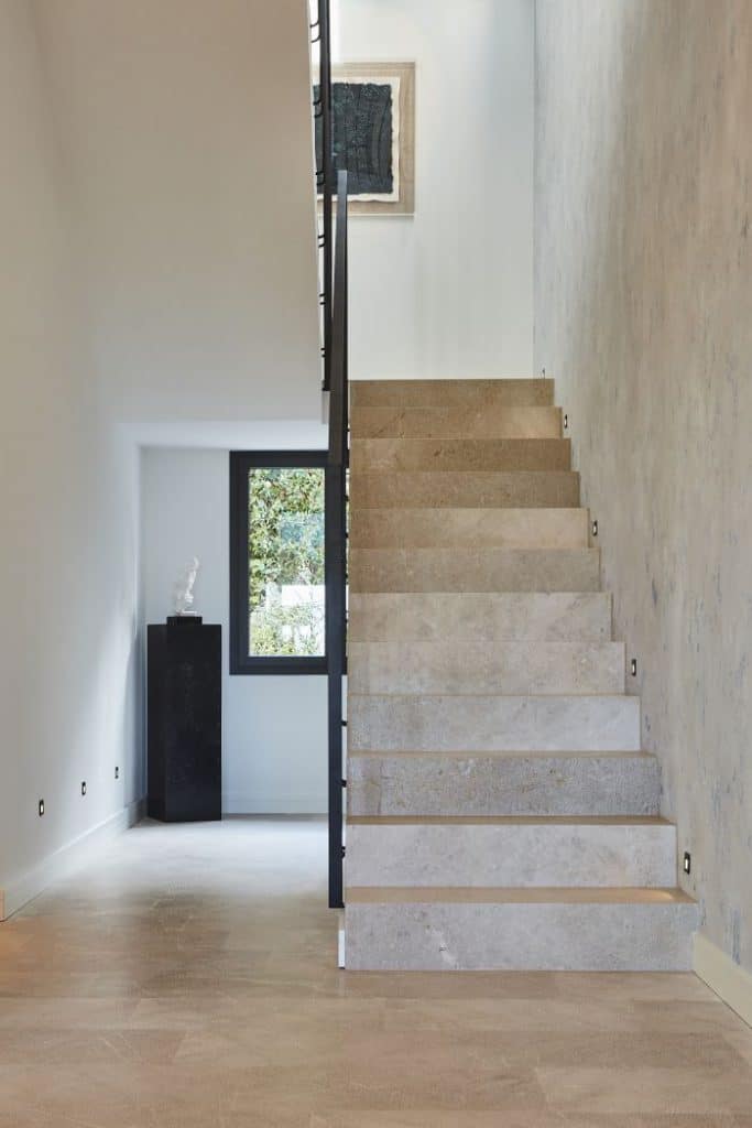 A stone staircase with metal handrail in high ceiling entrance.