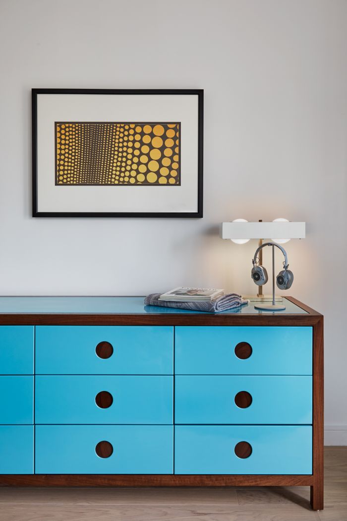 A bright blue lacquered chest of drawers adds a pop of colour to this bedroom. 