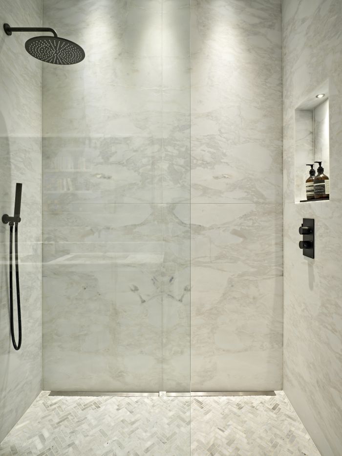 Booked match marble in shower with black fixtures and glass screen.
