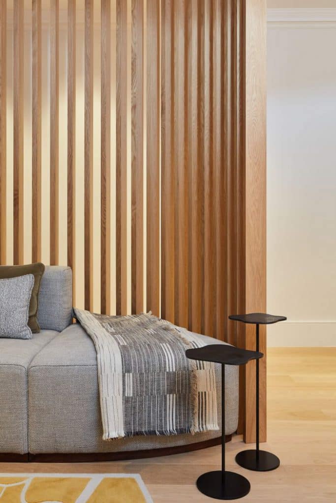 Floor to ceiling curved oak slatted wall with integrated uplight from John Cullen Lighting.