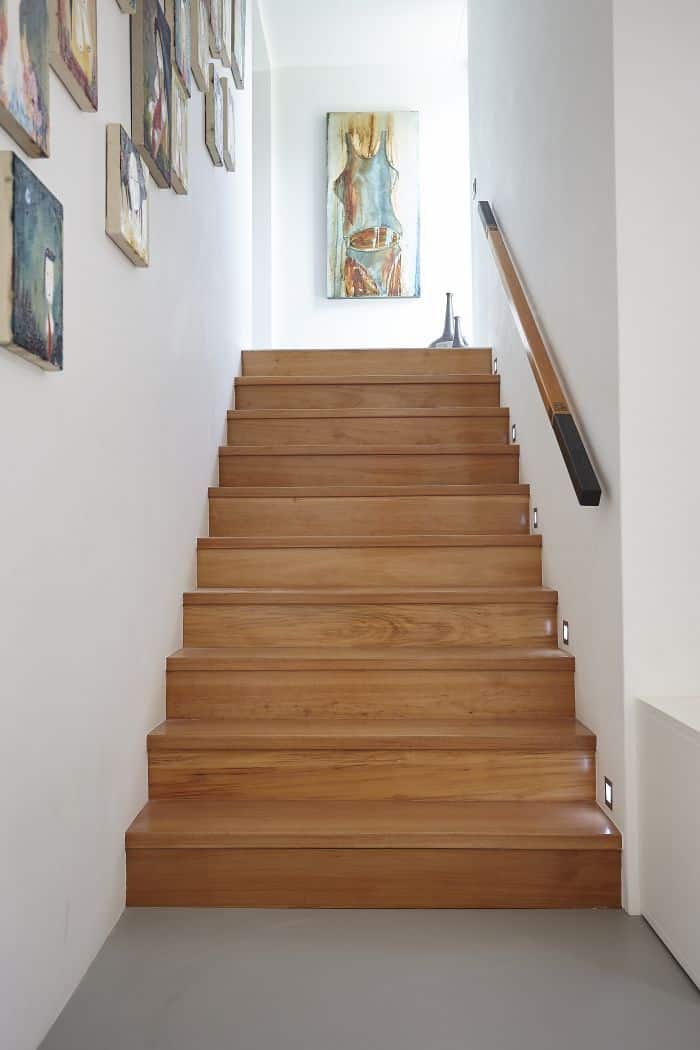 A wooden staircase and gallery wall of oil paintings. 