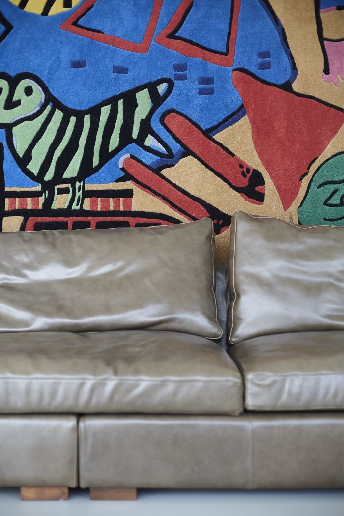 A bespoke leather sofa with Danish Tapestry hung on wall. 