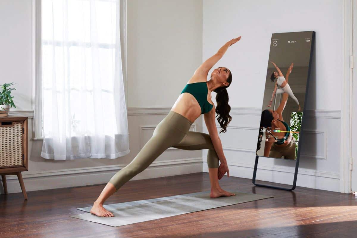 Woman using the Mirror for virtual yoga class in home gym