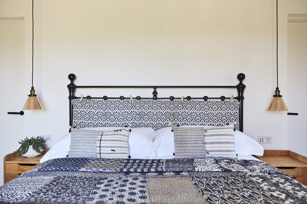 Coastal style bedroom with pillowed cast iron headboard.