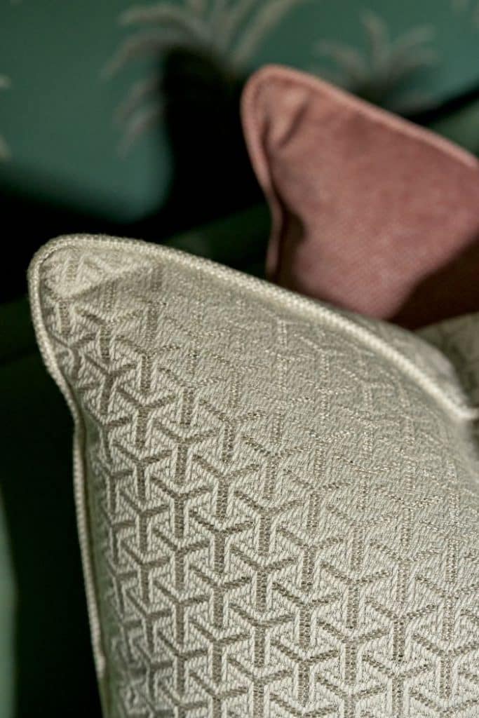 Up close image of scatter cushions from Sophie Paterson range at Andrew Martin. A beautiful gold cushion with subtle geometric patterns overlaps a dusty rose cushion creating a sophisticated, charming aesthetic.