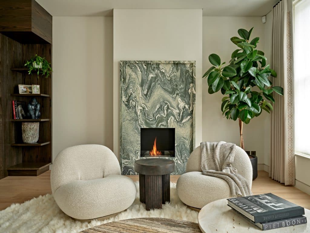 Living room with neutral tones and natural light. The statement piece of the room is the green marble fireplace.