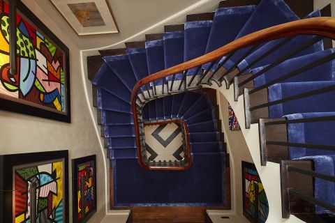 A photograph of a period staircase with blue carpet from above.