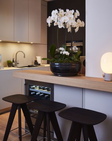 Bulthaup Kitchen from Kitchen Architecture with breakfast bar. The breakfast bar is decorated with beautiful white orchids. In the kitchen the lead colours are neutrals, blacks and whites.