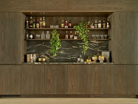 Black marble and dark wooden bar decorated with botanicals.