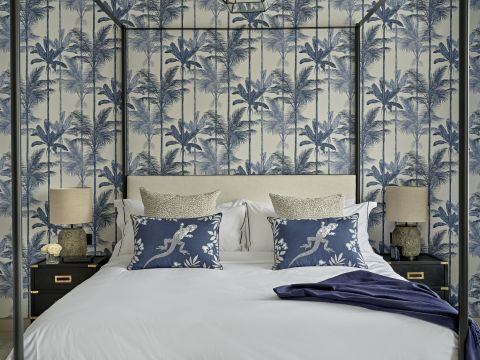 A luxury guest bedroom with four posted bed and blue Graham & Brown wallpaper.