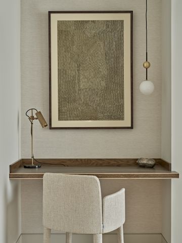 Study desk decorated with desk light, A neutral tone art piece and a hanging pendant light.