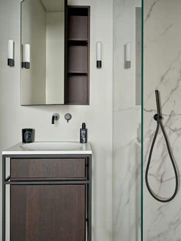 Bathroom segment which shows the dark cabinets and the marble pattern in the shower.