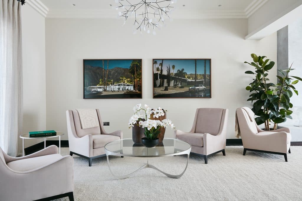 Neutral reception room with blush pink armchairs and colourful artworks.