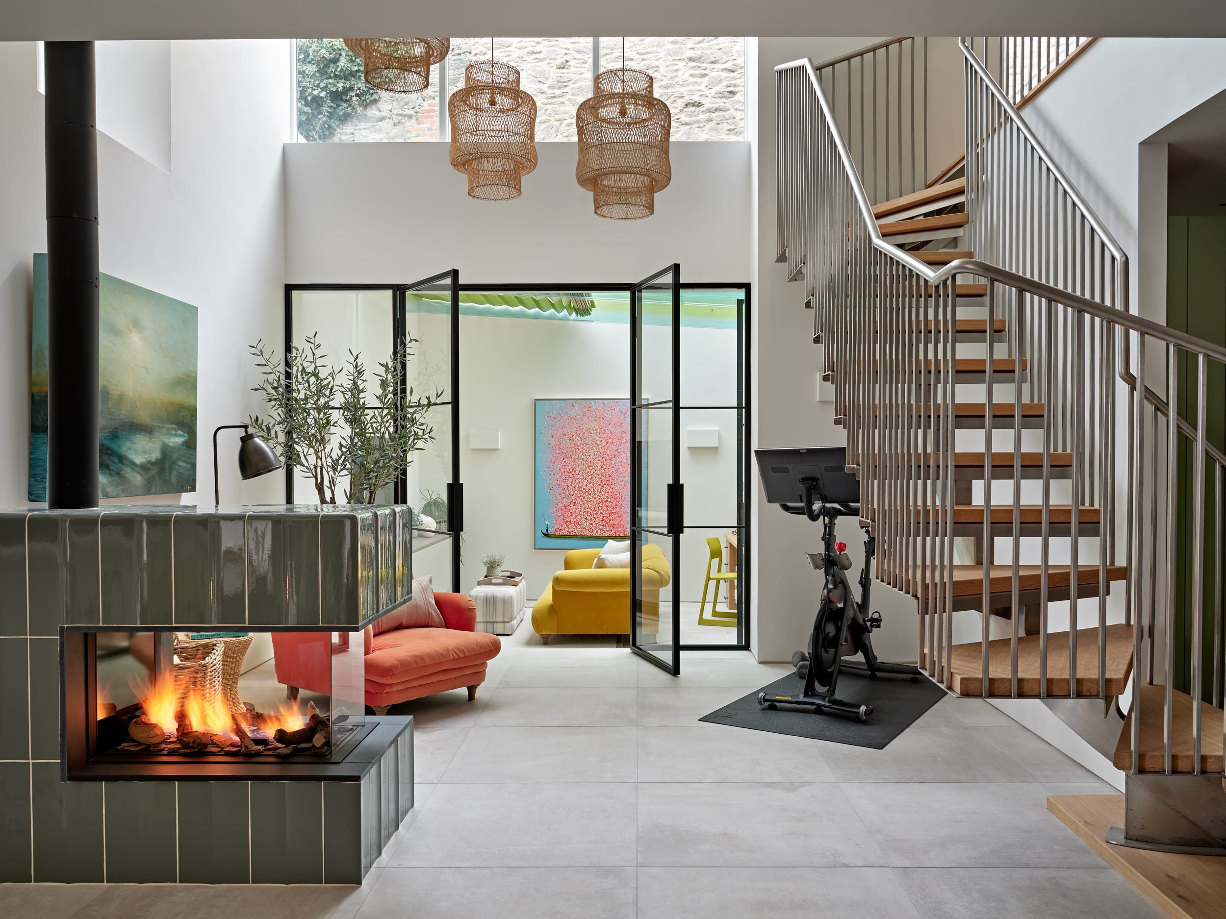 Airy living space separated by green tiled fireplace.