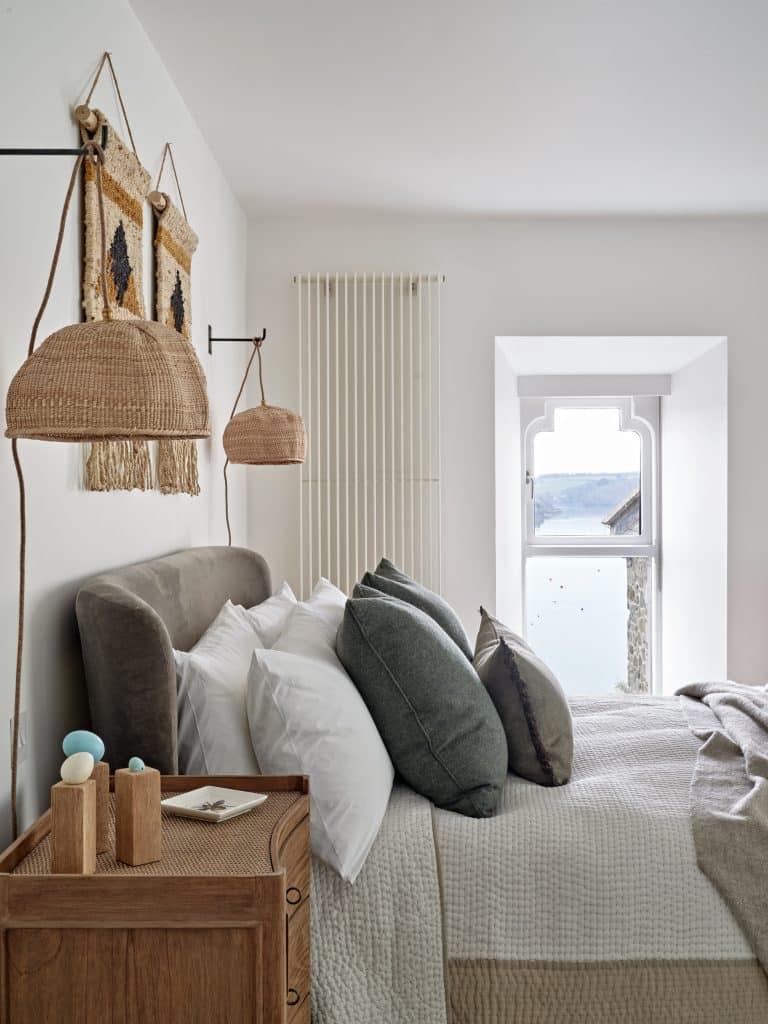 Neutral bedroom in coastal style seaside house. The bedroom is decorated with rattan accents.