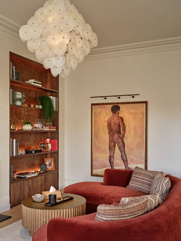 Beautiful large oil painting decorates the wall of a mid century modern living room. The warm tones of the painting is aligning with the tones in the room.