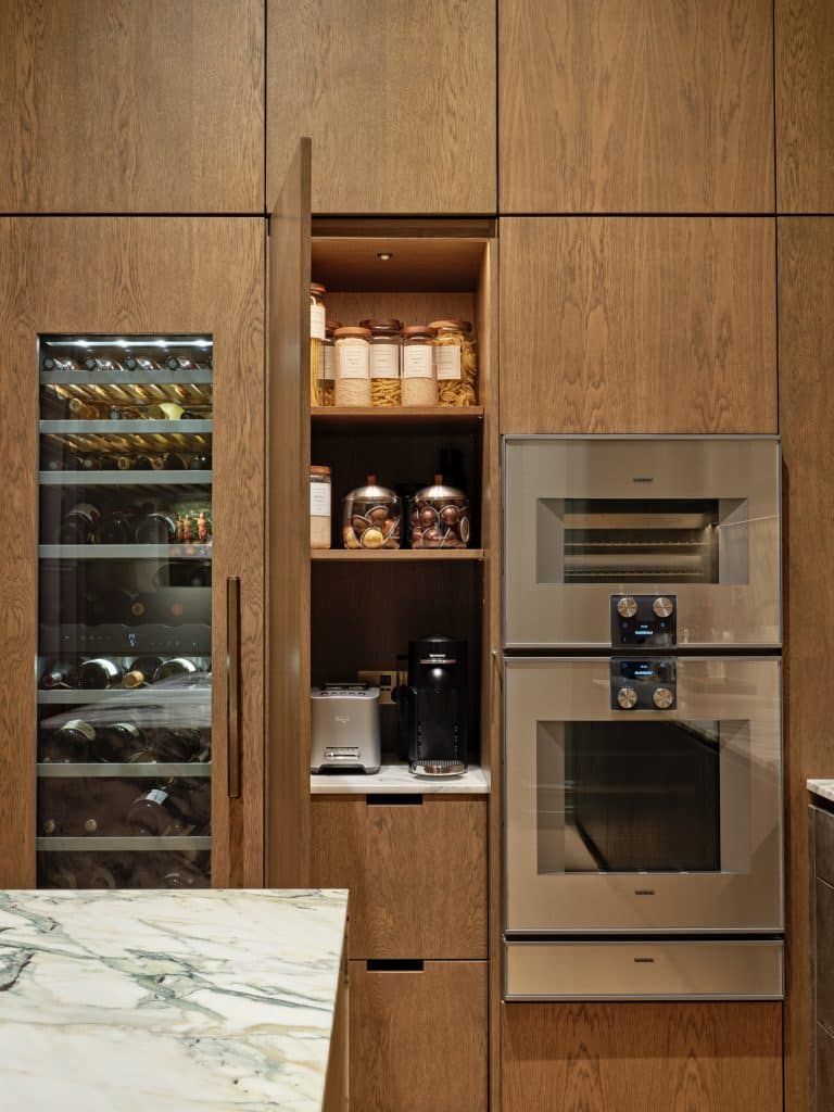 Built in wine fridge, steam oven and regular oven in bespoke cabinetry in kitchen. In between the appliances there is a hidden pantry and coffee station.