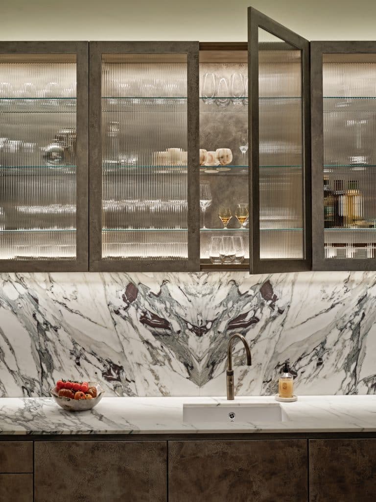 Marble kitchen counter and hand-painted pitted champagne liquid leaf finished cabinets.