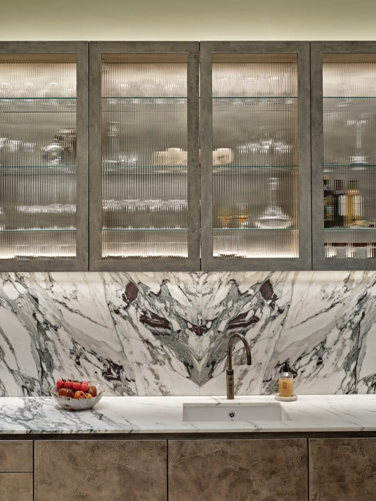 Marble kitchen counter and hand-painted pitted champagne liquid leaf finished cabinets.